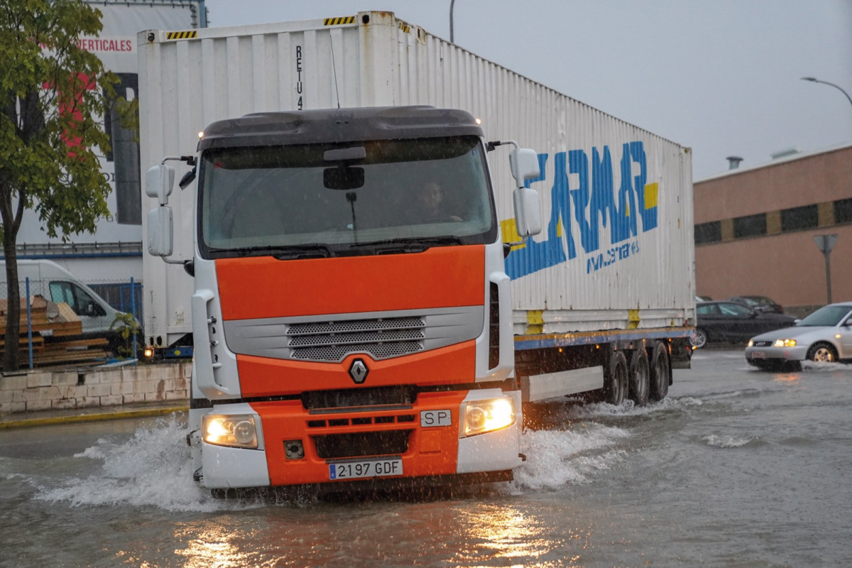 Un camión transita con dificultades por la calle Villa de Madrid inundada durante una tormenta