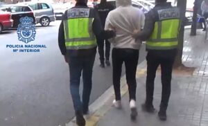 Uno de los detenidos es conducido por dos agentes de la Policía Nacional