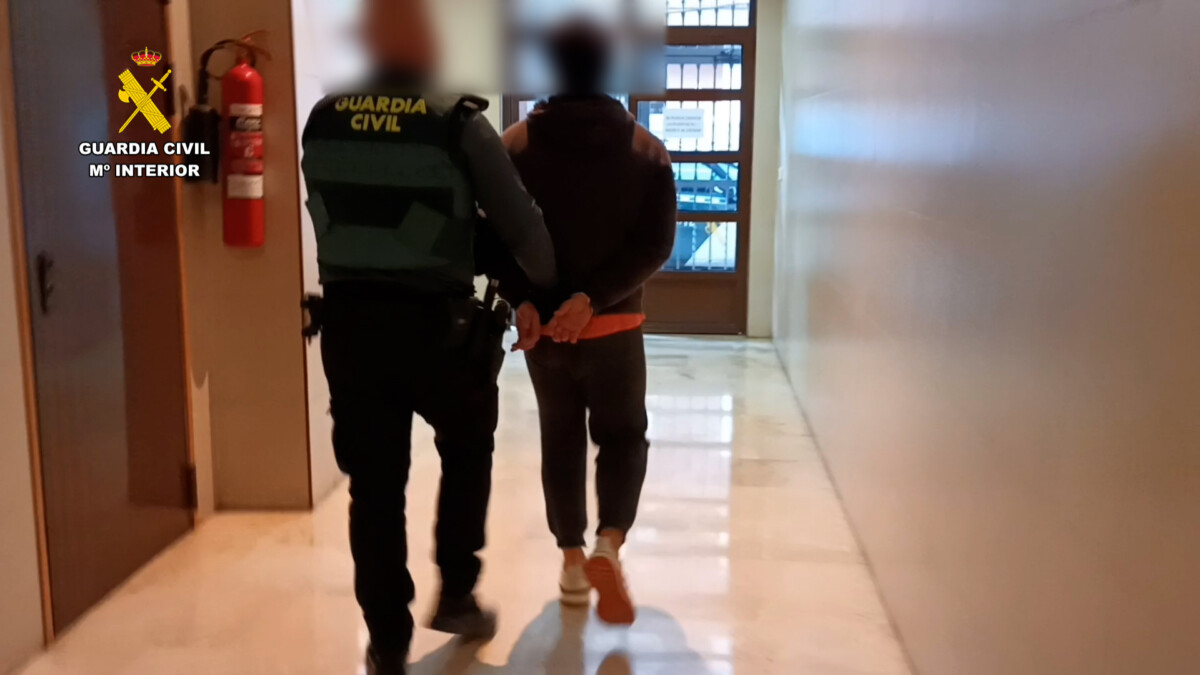 Un agente de la Guardia Civil conduce a uno de los detenidos