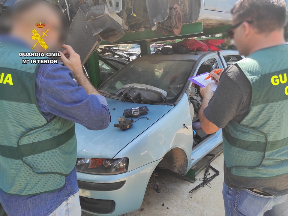 Dos agentes de la Guardia Civil inspeccionan un desguace