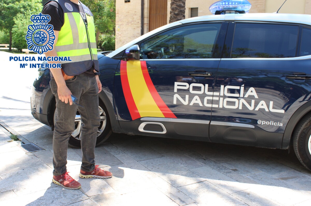 Agente de la Policía Nacional junto a un coche patrulla
