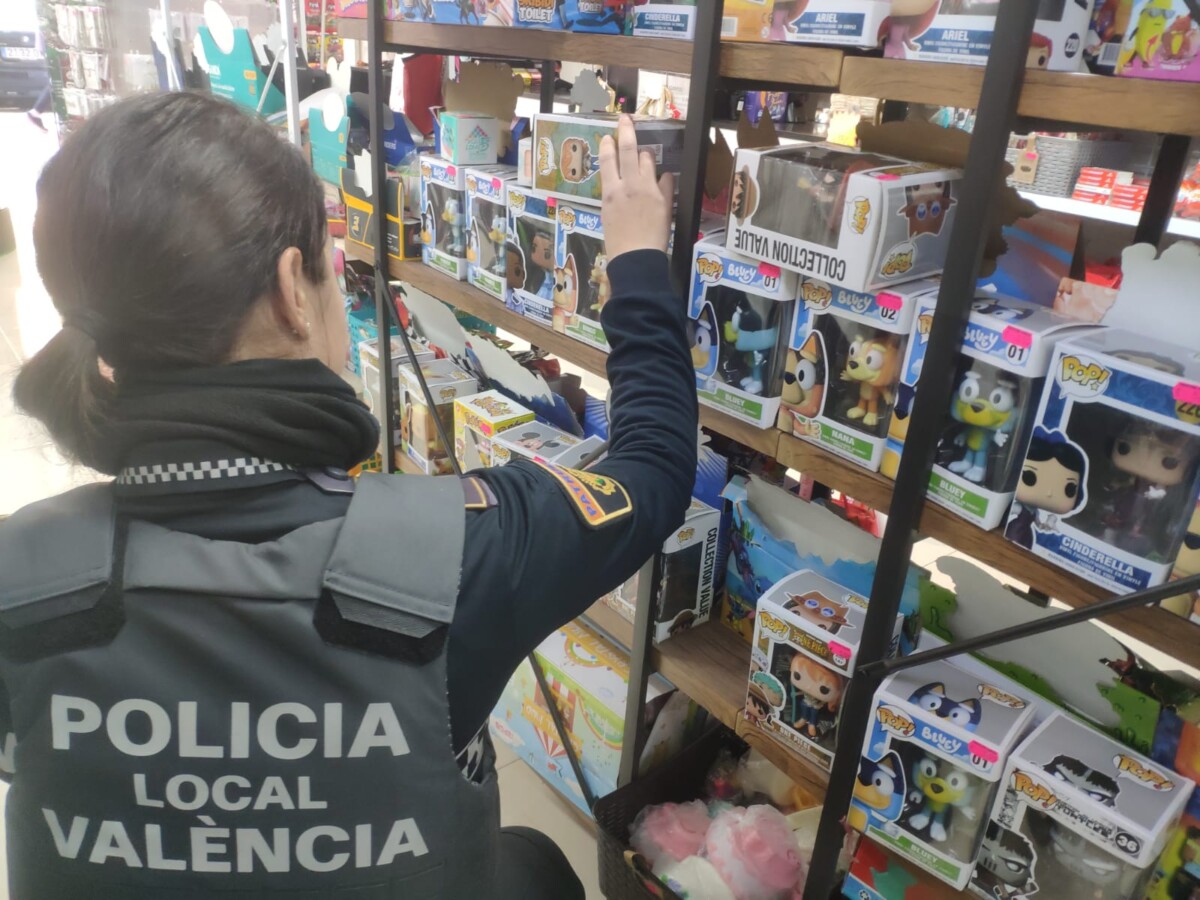 Una agente de la Policía Local inspecciona muñecos de Funko en un local de Valencia