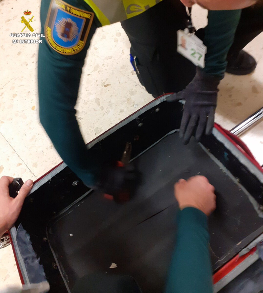 Un agente de la Guardia Civil inspecciona la maleta de un pasajero