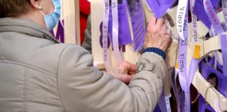 Persona colocando lazo morado en un memorial de mujeres
