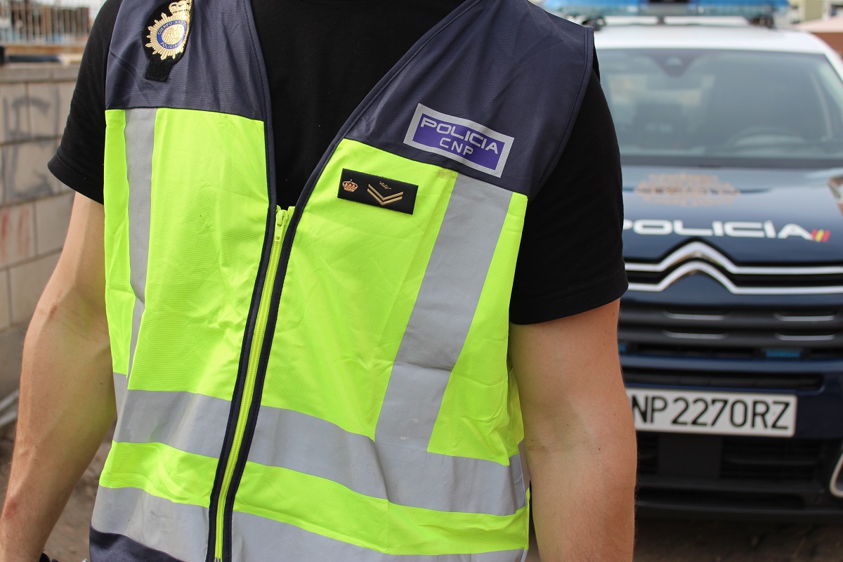 Agente de la Policía Nacional junto a un coche patrulla