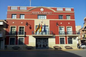 Edificio del Ayuntamiento de Rafelbunyol con banderas y cielo azul