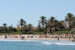 Playa del Puig con palmeras y personas disfrutando del sol