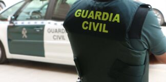 Agente de la Guardia Civil junto a un vehículo patrullero