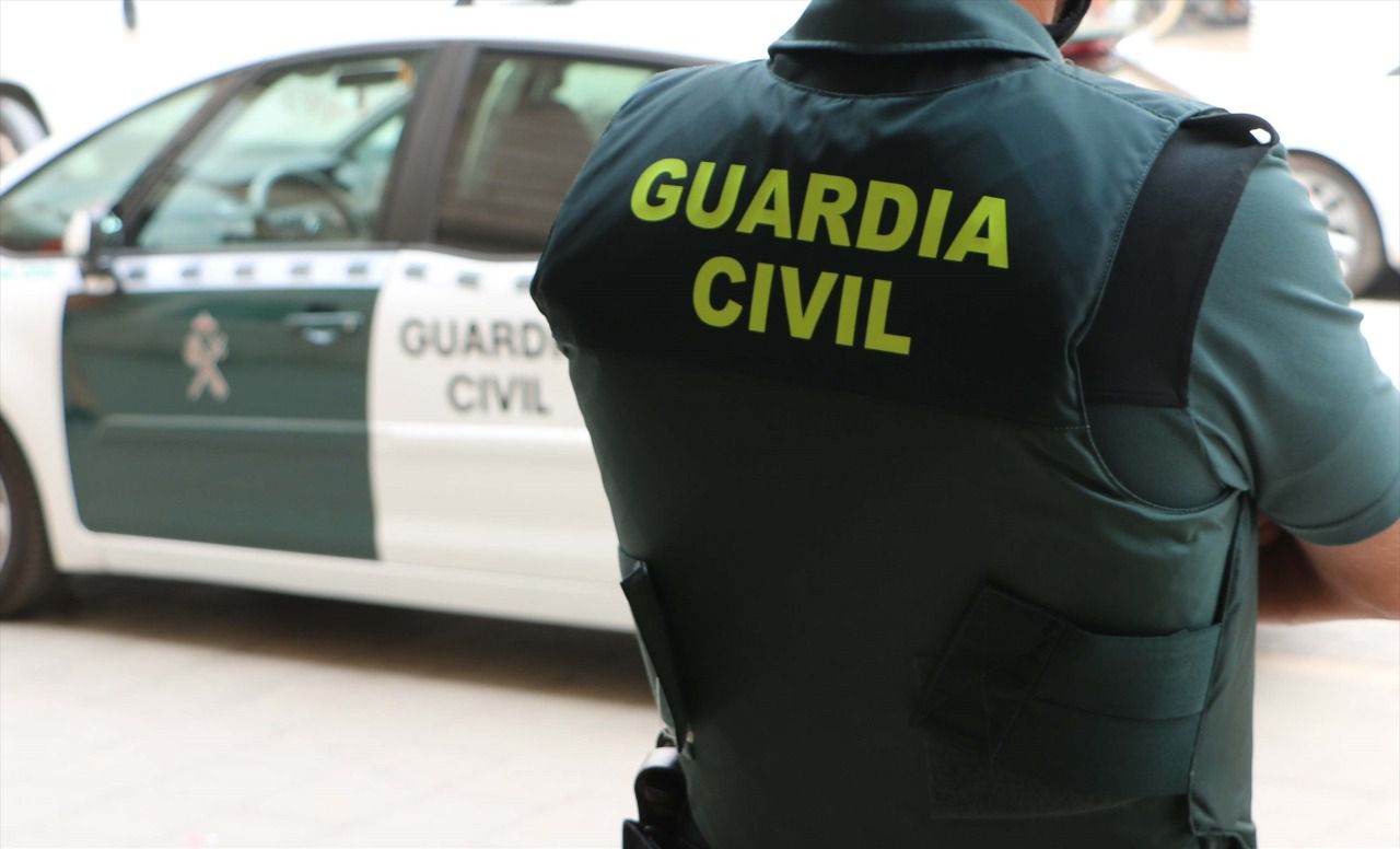Agente de la Guardia Civil junto a un coche patrulla