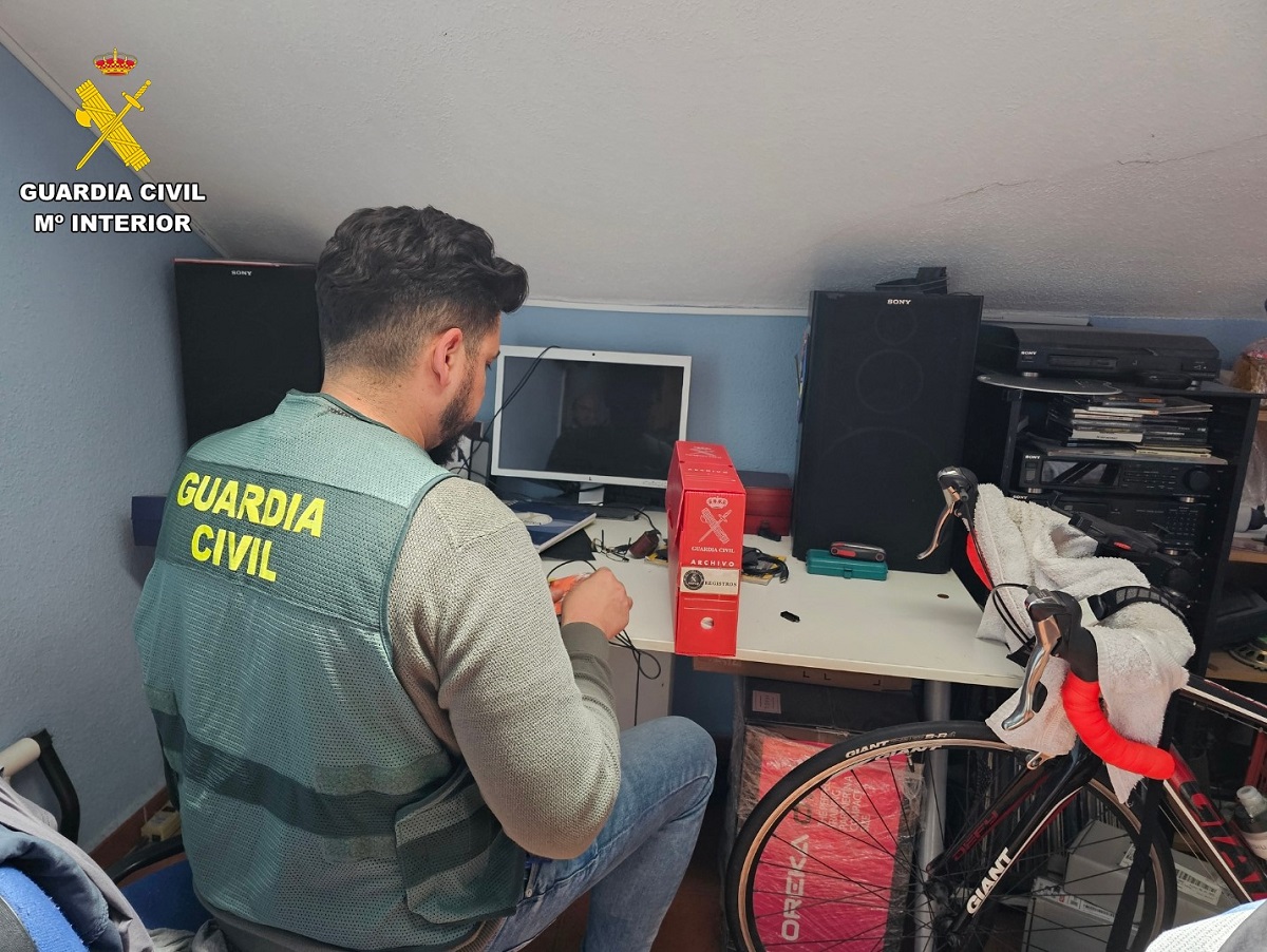 Un agente de la Guardia Civil inspecciona el equipo informático de la detenida
