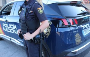 Una agente de la Policía Nacional junto a un coche patrulla