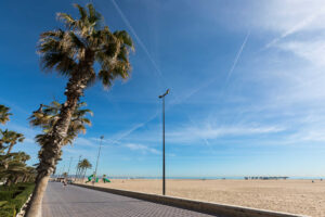 Vista de la playa del Cabanyal en Valencia con palmeras y cielo azul