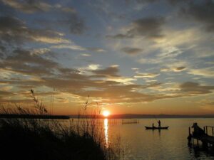 Puesta de sol en la Albufera de Valencia con barcas y vegetación