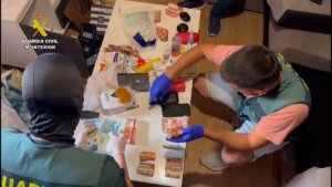 Dos agentes de la Guardia Civil inspeccionan dinero y droga encontrada en el registro