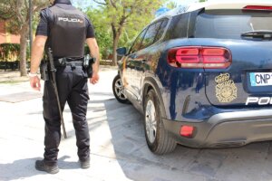 agente de la Policía Nacional junto a un coche patrulla