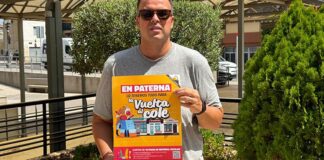 Hombre sosteniendo un cartel de la campaña de vuelta al cole en Paterna.