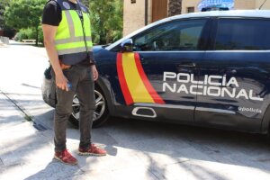 Agente junto a un coche patrulla de la Policía Nacional