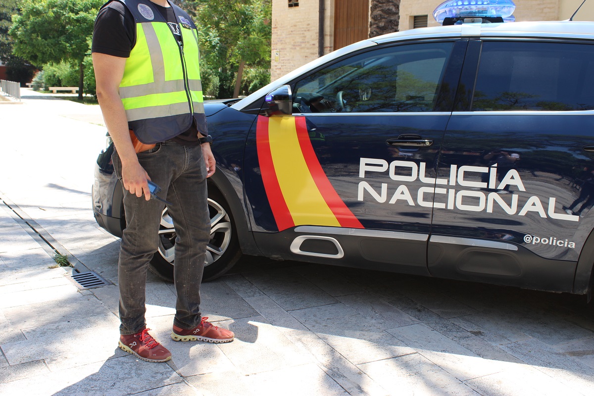 Agente junto a un coche patrulla de la Policía Nacional