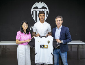 El nuevo jugador del Valencia Enzo Barrenechea posa con la camiseta de su nuevo club junto a la presidenta Layhoon Chan y el director deportivo Miguel Ángel Corona. Foto cedida por el Valencia CF.