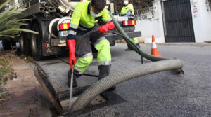 Trabajador limpiando un imbornal con camión de succión en Valencia
