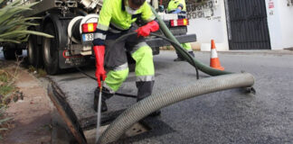 Trabajador limpiando un imbornal con camión de succión en Valencia