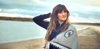 Mujer con cabello largo y suelto, posando en la playa al atardecer