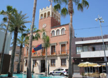 El proyecto Green-TDigital lleva a Alcàsser a los premios CNIS 2026 por innovación administrativa Vista del ayuntamiento de Alcàsser con palmeras y banderas