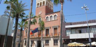 Vista del ayuntamiento de Alcàsser con palmeras y banderas