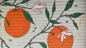 Pintura de naranjas y flores en una persiana de comercio en Russafa.