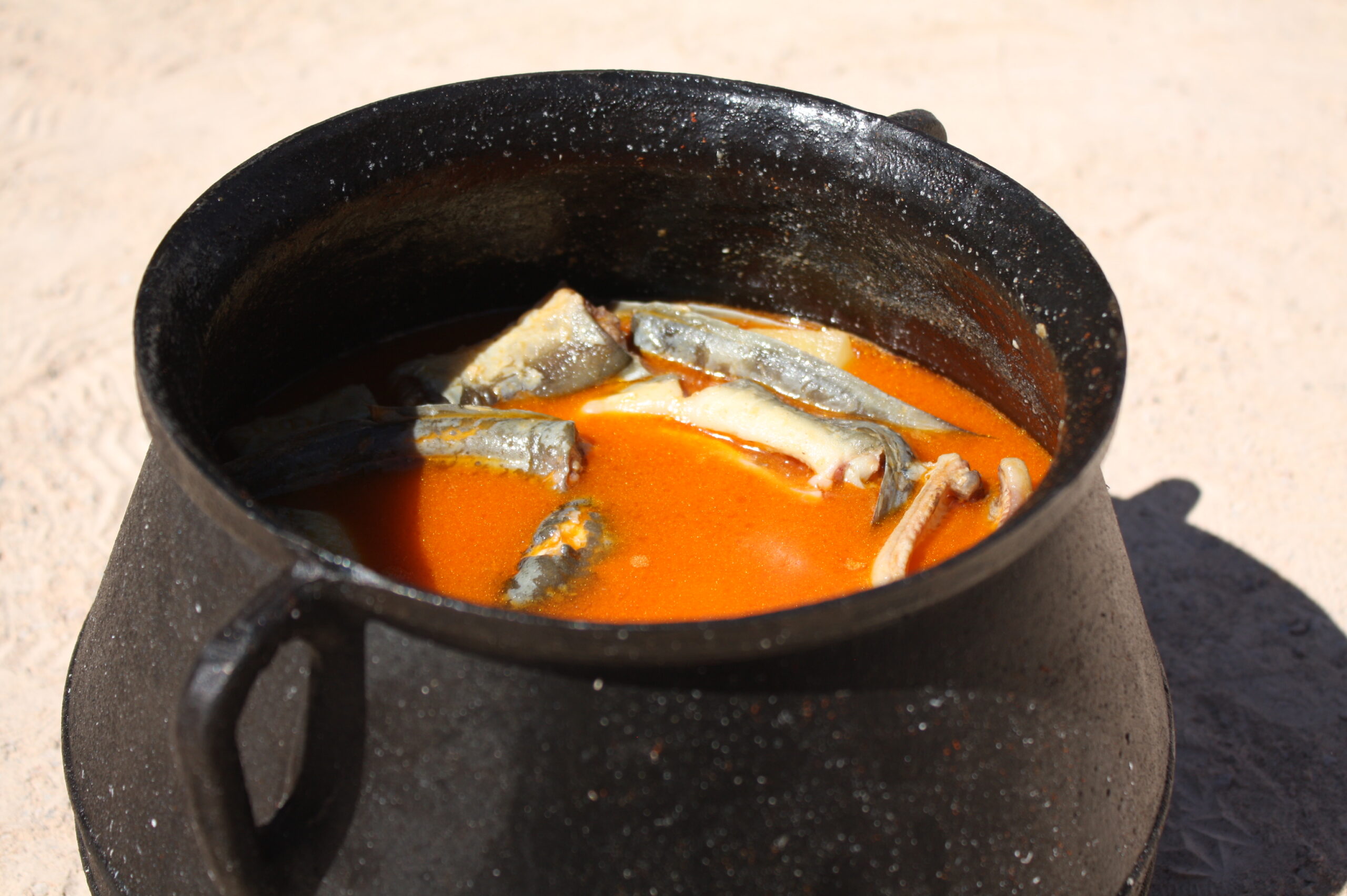 Guiso de allipebre en una olla negra con anguilas y caldo