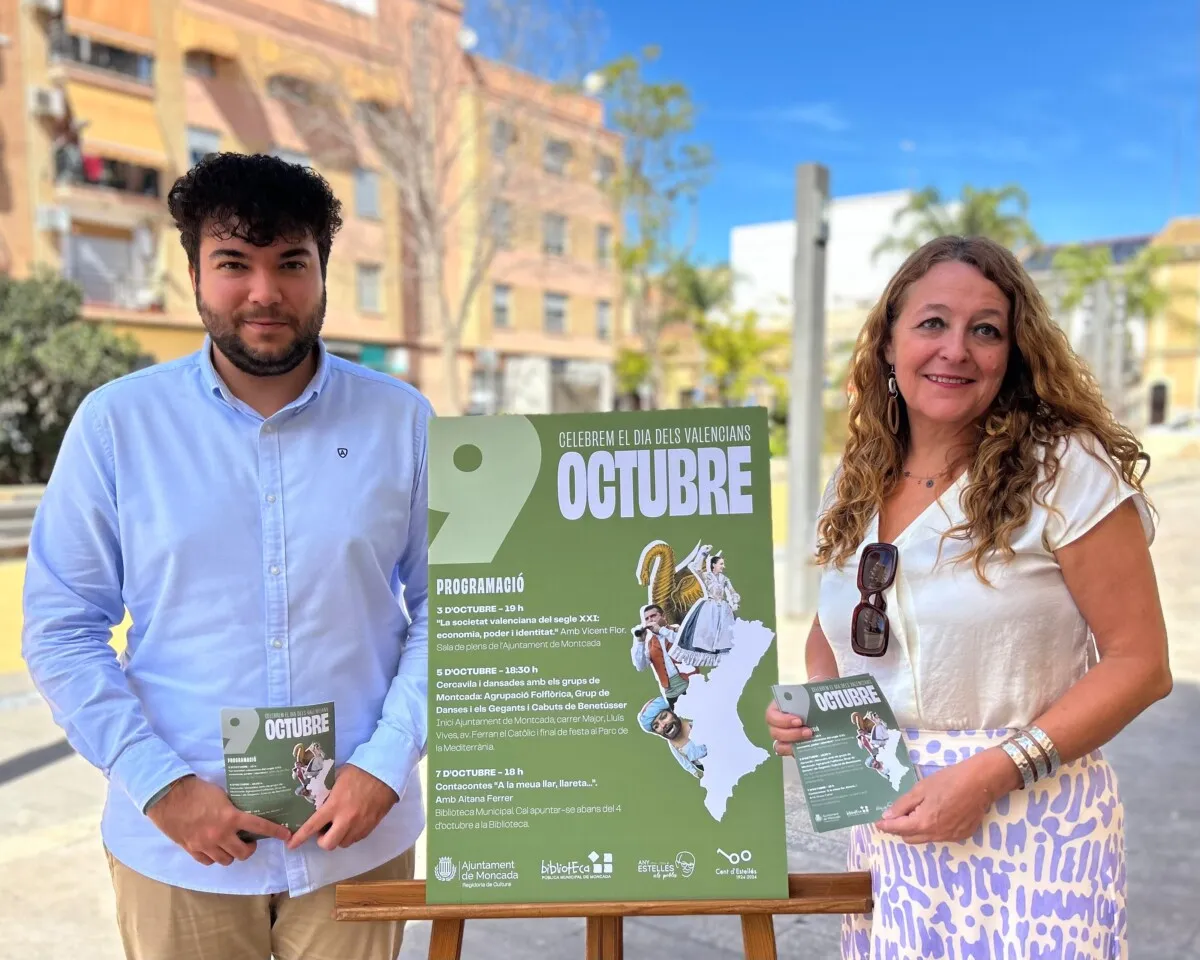 Dos personas sosteniendo un cartel sobre la celebración del 9 de octubre en Moncada