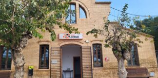 Fachada del Antic Escorxador en Foios con árboles y banco