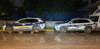 Dos vehículos de policía local en Benetússer en una calle embarrada