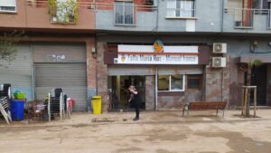 Persona limpiando la entrada del casal faller afectado por la dana