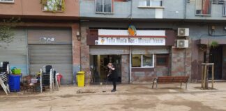 Persona limpiando la entrada del casal faller afectado por la dana