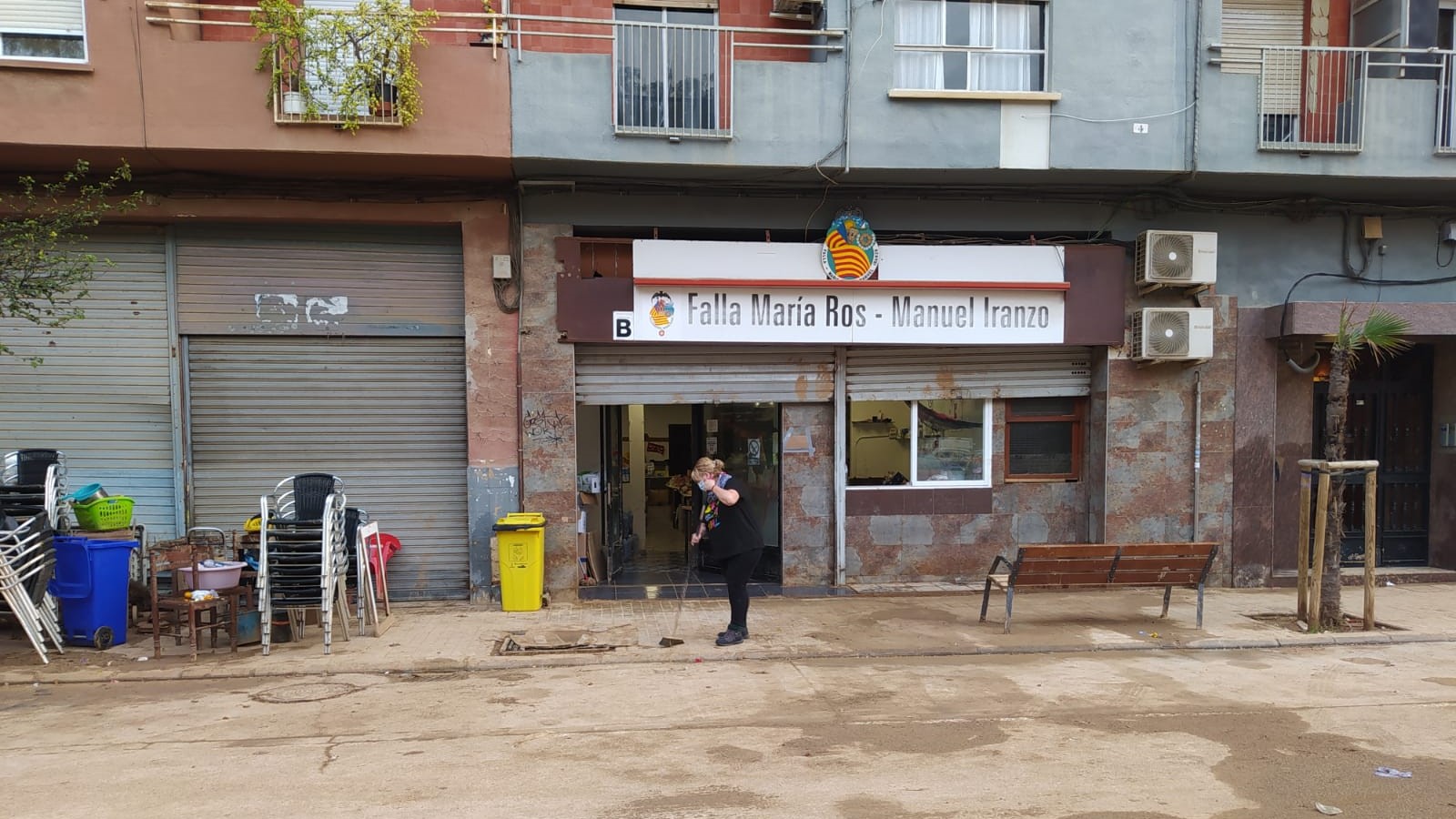 Persona limpiando la entrada del casal faller afectado por la dana