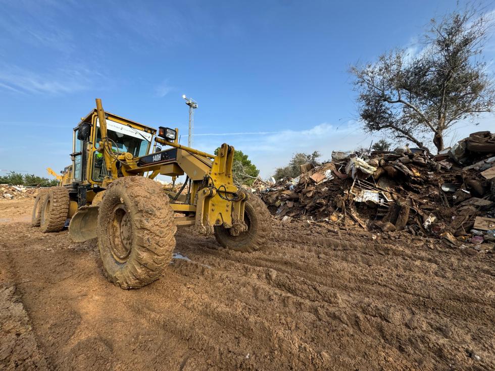 Máquina de construcción en un terreno con lodo y escombros