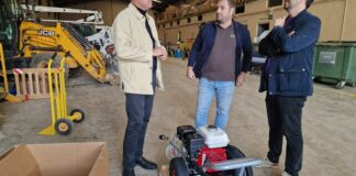 Tres hombres conversando sobre hidrolimpiadores donados en un almacén