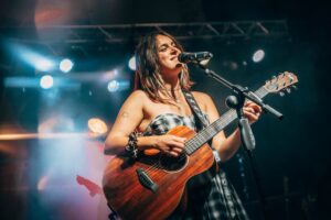 Cantautora Esther actuando en un concierto solidario con guitarra