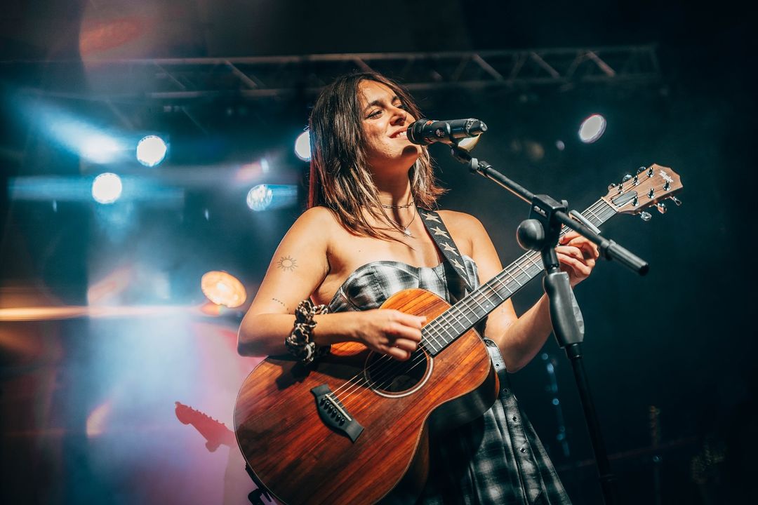 Cantautora Esther actuando en un concierto solidario con guitarra