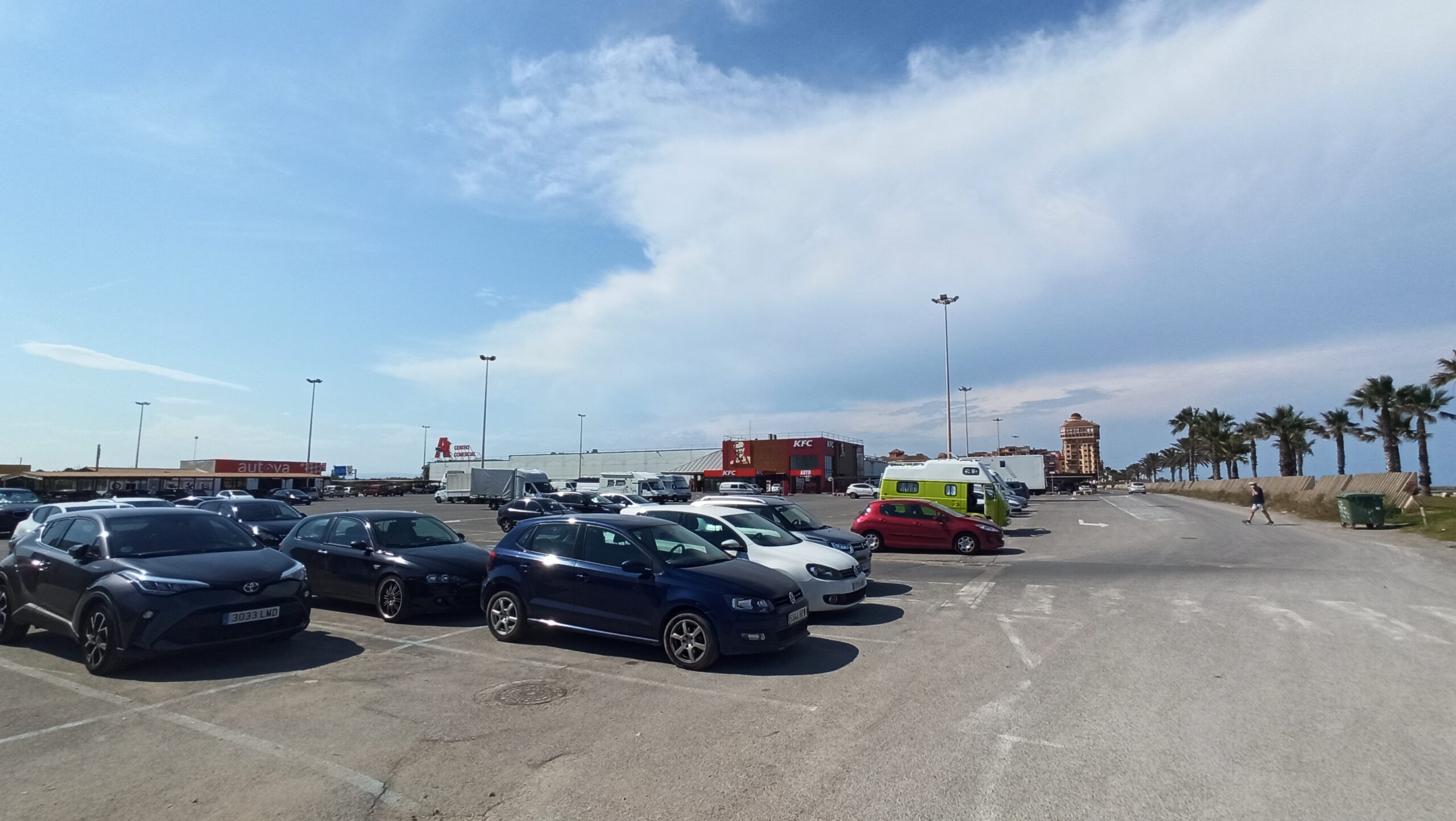 Vista del aparcamiento en Port Saplaya con varios coches y edificios al fondo