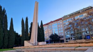 Monumento a las víctimas de las riadas en Valencia con árboles y edificios de fondo