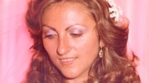 Mujer con cabello rizado y maquillaje suave en un fondo rosa