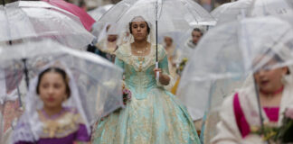 Mujeres con trajes tradicionales y paraguas en la ofrenda de flores