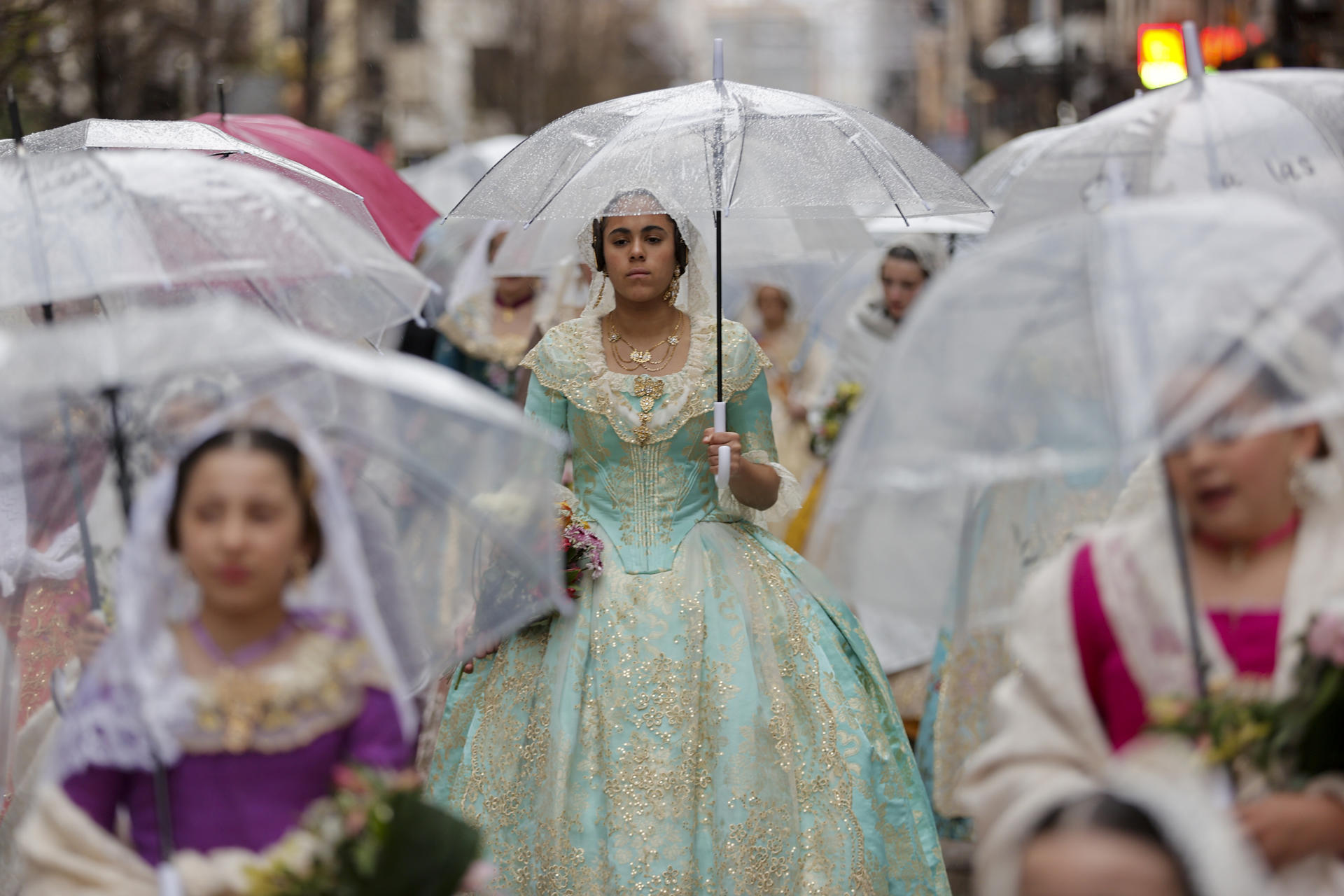 Mujeres con trajes tradicionales y paraguas en la ofrenda de flores