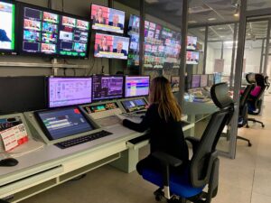 Mujer trabajando en un control de televisión con múltiples pantallas