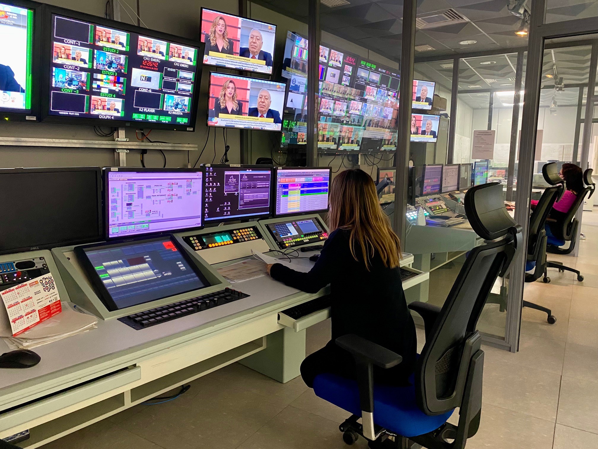 Mujer trabajando en un control de televisión con múltiples pantallas
