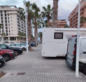 Caravana estacionada en la playa de la Patacona con edificios de fondo
