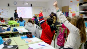 Estudiantes en un aula levantando la mano para participar