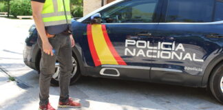 Agente de policía junto a un vehículo de la Policía Nacional